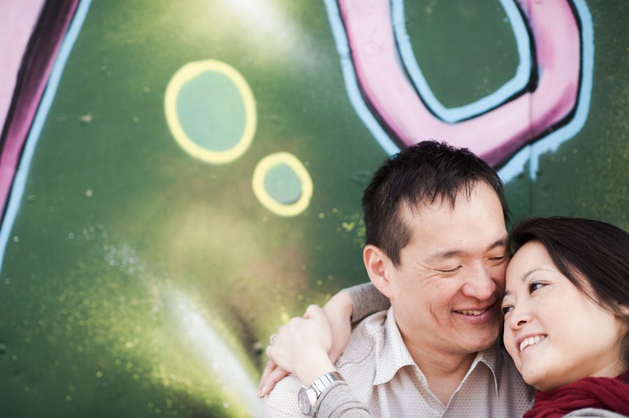Lisa and Kai pose in front of a graffiti wall during their engagement session in Williamsburg with awesome New York City wedding photographer Ben Lau.