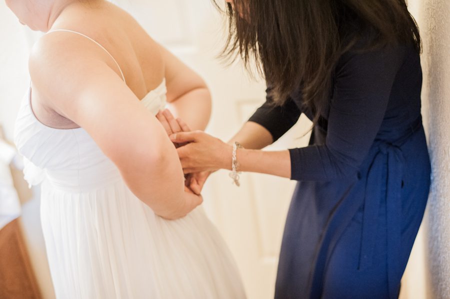 Bride is helped into her dress on her wedding day in Washington DC. Captured by Ben Lau Photography.
