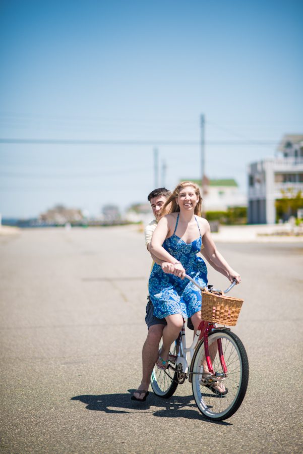 Mike and Alexis ride a bike during their engagement session on Long Beach Island with awesome NJ wedding photographer Ben Lau.