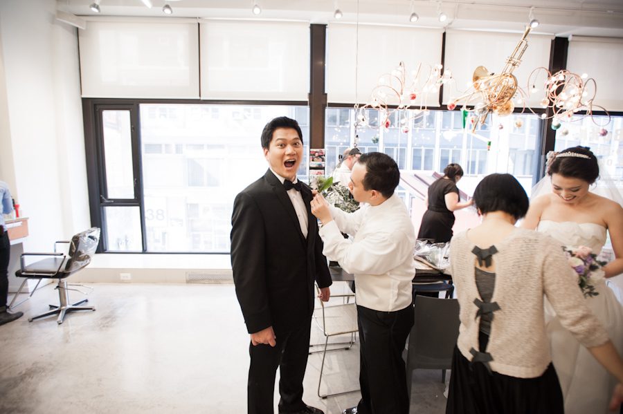 The groom gestures towards the camera on his wedding day. Captured by awesome New York City wedding photographer Ben Lau.