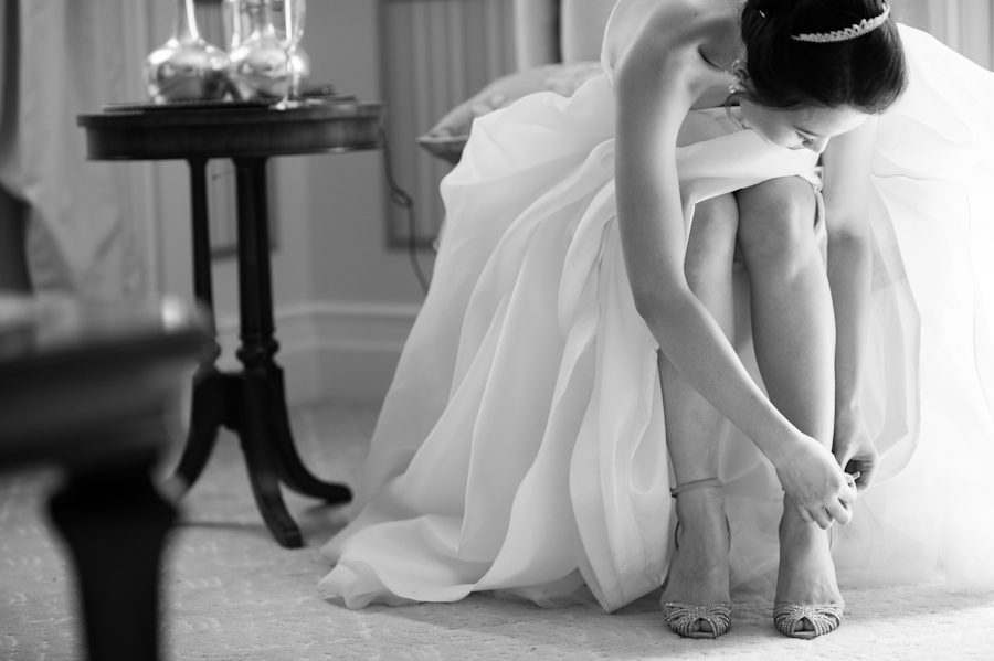 Bride puts on her shoes on her wedding day at Snug Harbor in Staten Island. Captured by awesome New York City wedding photographer.