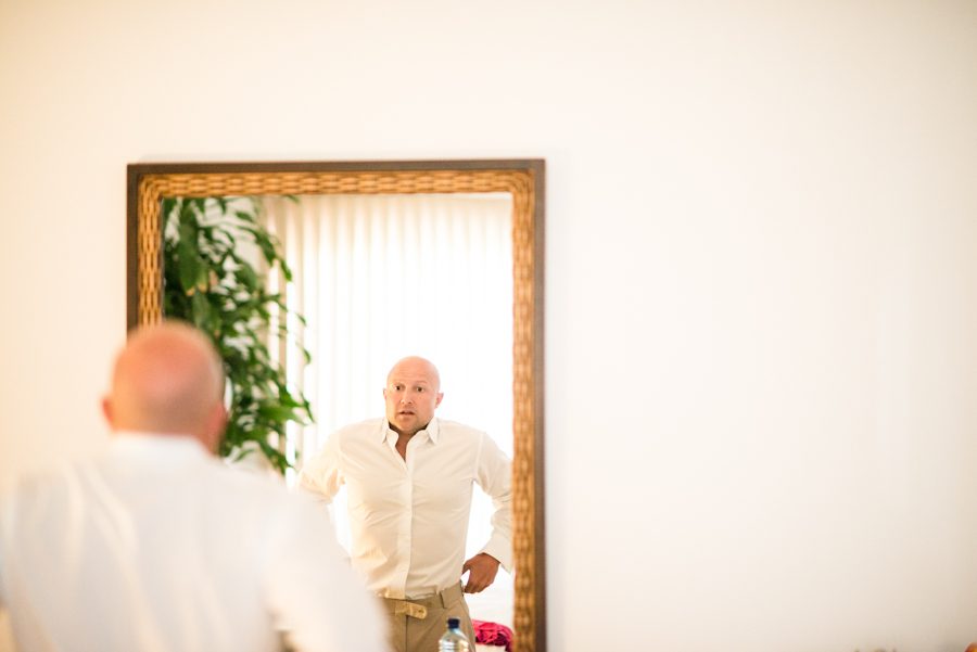 Groom gets ready in front of a mirror before his wedding ceremony at the CuisinArt Resort & Spa in Anguilla. Captured by Caribbean destination wedding photographer Ben Lau.
