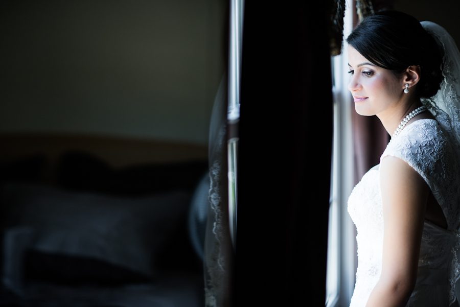 Bride looks out the window. Captured by awesome NJ wedding photographer Ben Lau.