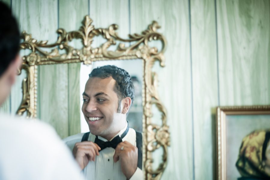 Groom Sam gets ready in front of a mirror on his wedding day in Jersey City, NJ. Captured by awesome New Jersey wedding photographer Ben Lau.