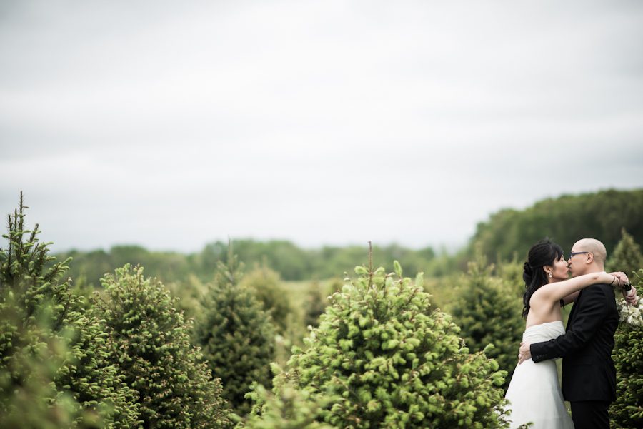 Bride and groom share a kiss in a field of trees on their wedding day in Princeton, NJ. Captured by awesome NJ wedding photographer Ben Lau.
