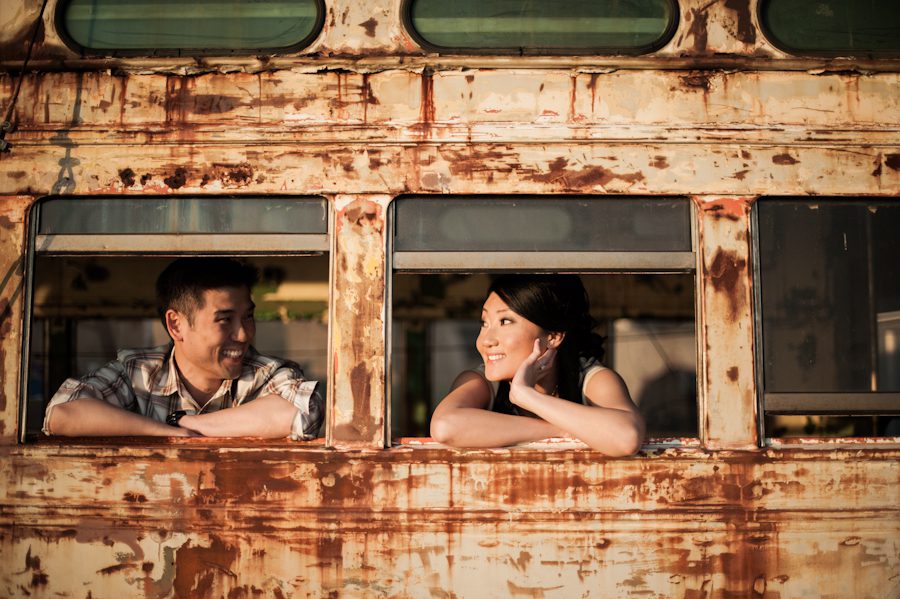 Yumi and Alan pose inside the windows of an abandoned train during their engagement session in Red Hook. Captured by awesome NYC wedding photographer Ben Lau.