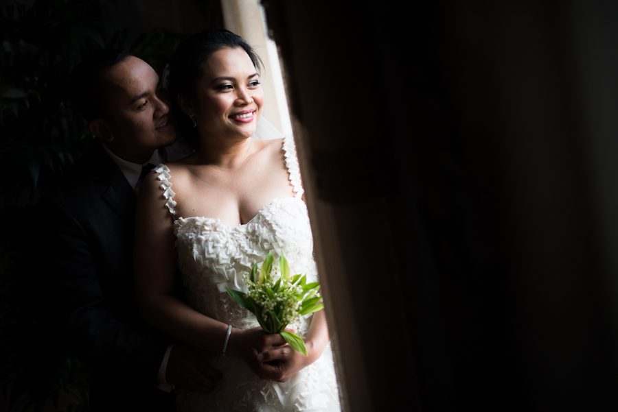 Bride and groom pose near a window at the Oxon Hill Manor in Oxon Hill, MD. Captured by awesome NJ wedding Photographer Ben Lau.
