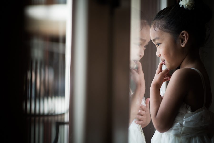 Flower girl looks out window during prep at the Gaylord National Resort in Washington DC. Captured be awesome NJ wedding photographer Ben Lau.
