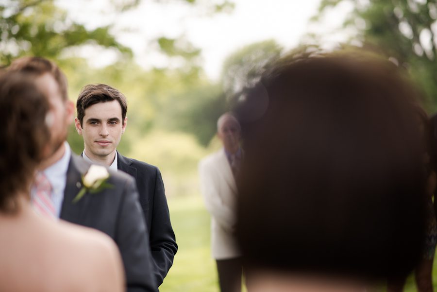 Best Man looks on during wedding ceremony at the Bayard Cutting Arboretum in Long Island, NY. Captured by awesome NJ wedding photographer Ben Lau.