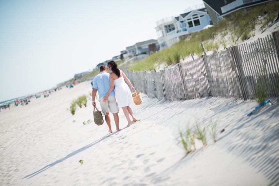 Nicole and Gregg walk along a sand dune in Long Beach Island, NJ during their engagement session with Ben Lau Photography.