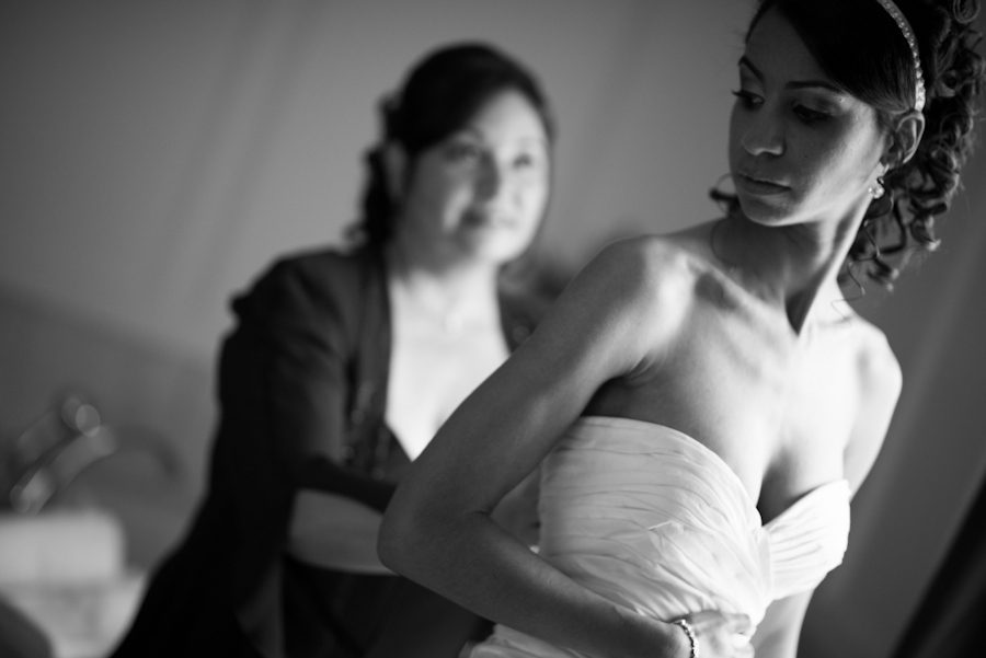 Mom helps her daughter into her dress on her wedding day at The Manor in West Orange. Captured by best NJ wedding photographer Ben Lau.