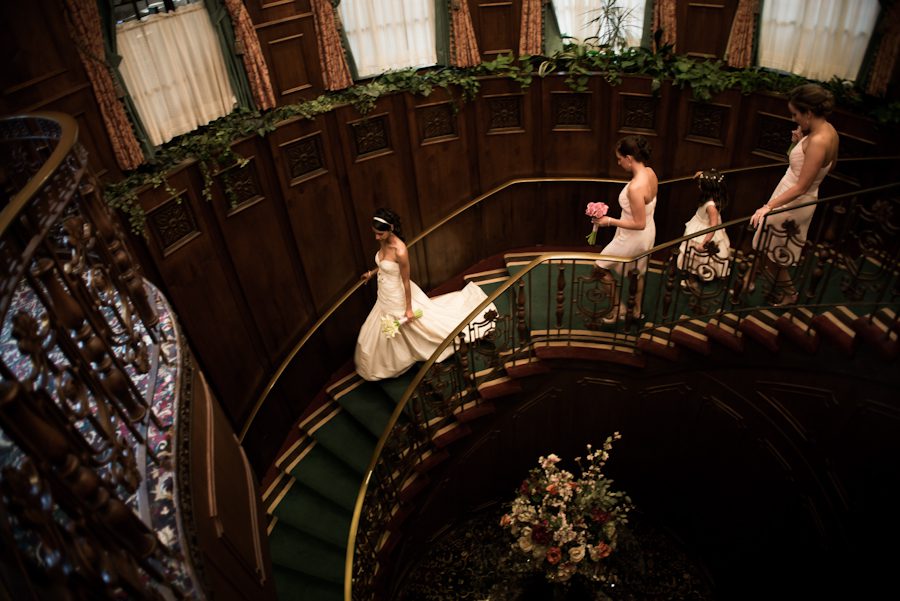 Bride makes her way down the stairs with her bridesmaids on her wedding day at The Manor in West Orange. Captured by best NJ wedding photographer Ben Lau.