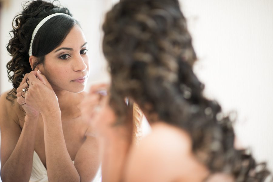 Bride puts on her earrings on her wedding day at The Manor in West Orange, NJ. Captured by awesome NJ wedding photographer Ben Lau.