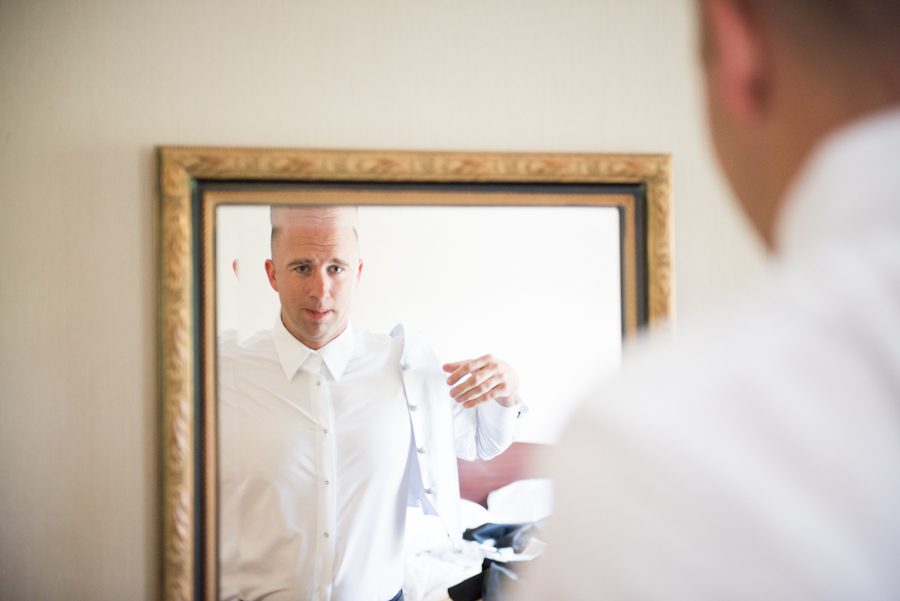 Groom puts on his jacket on his wedding day at The Manor in West Orange, NJ. Captured by awesome NJ wedding photographer Ben Lau.