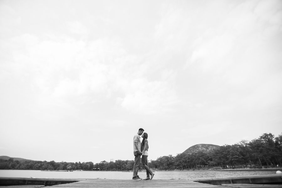 Sally and Terence stand on a pier at Bear Mountain, NY. Captured by awesome NJ wedding photographer Ben Lau.