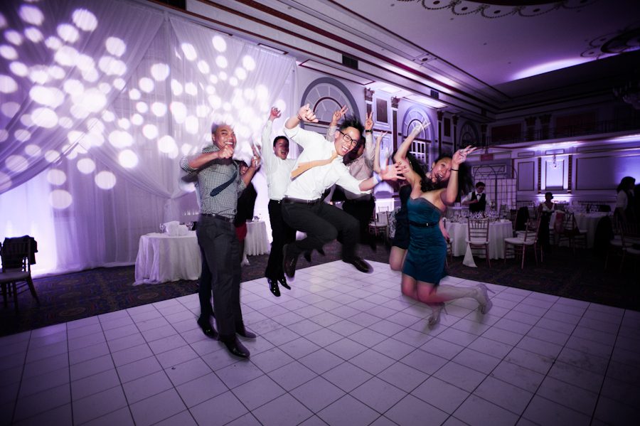 Guests do a jumping photo at a wedding reception at Le Windsor in Montreal, QC. Captured by destination wedding photographer Ben Lau.