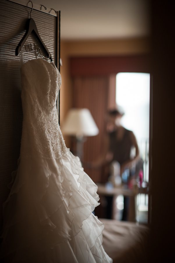 Bride's wedding dress hangs in her room before her ceremony at Herrington on the Bay in Chesapeake Beach, MD. Captured by NJ wedding photographer Ben Lau.