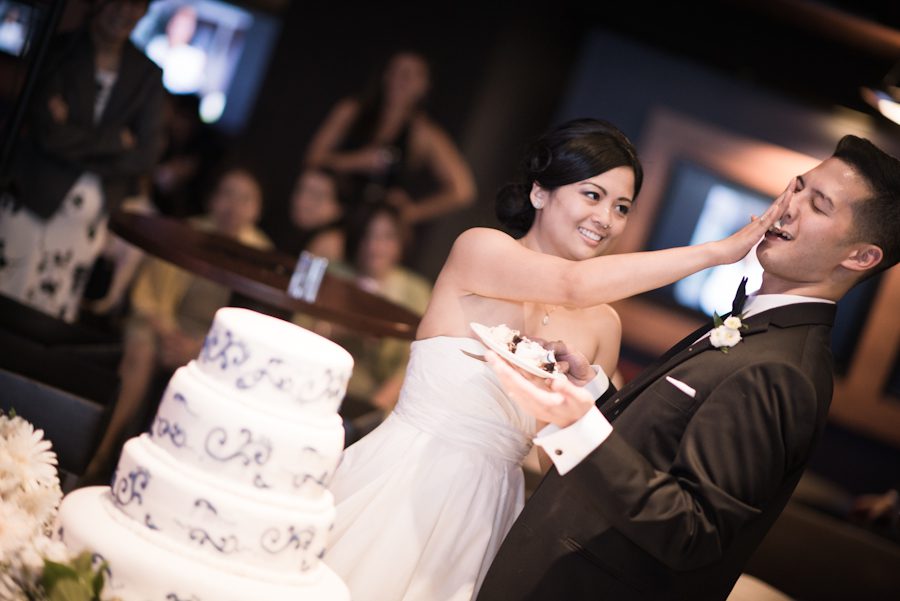 Bride smashes cake into the groom's face during a wedding at Ravens Stadium in Baltimore, MD. Captured by awesome Ben Lau Photography.