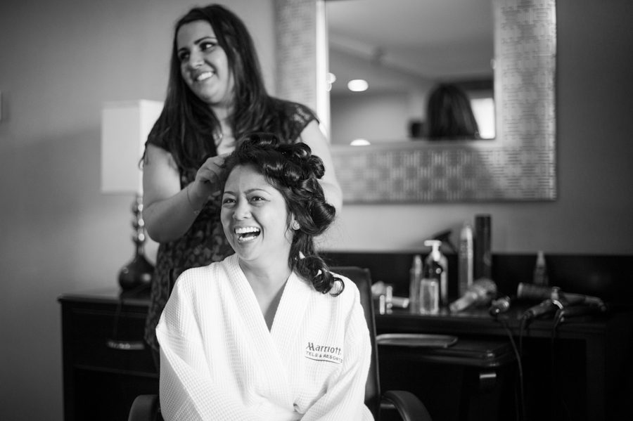 Bride laughs while getting her hair done on the morning of her wedding in Baltimore, MD. Captured by awesome Ben Lau Photography.