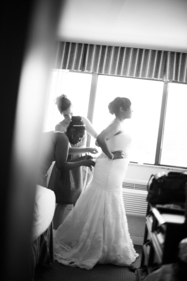Bride puts on her dress before her wedding at the Coral House in Baldwin, NY. Captured by awesome NJ wedding photographer Ben Lau.