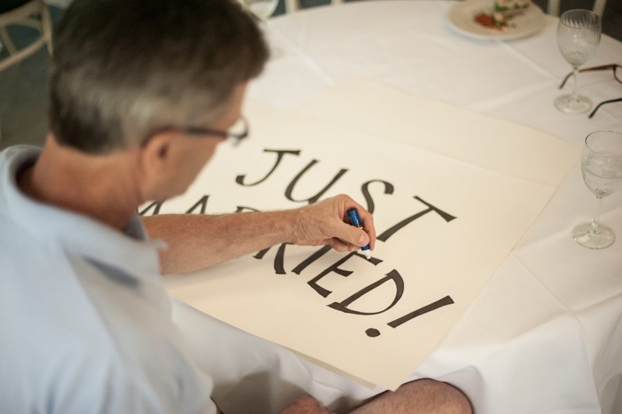 Father of bride prepares signs for Katie and Jason's wedding day at Ram's Head Inn on Shelter Island, NY. Captured by Northern NJ wedding photographer Ben Lau.