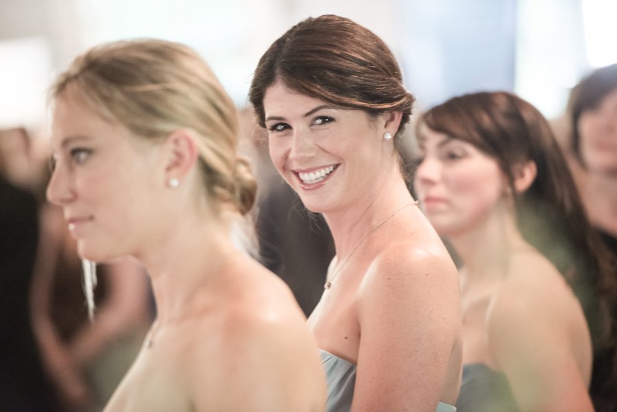 Bridesmaid smiles during a wedding ceremony on Shelter Island. Captured by Northern NJ wedding photographer Ben Lau.