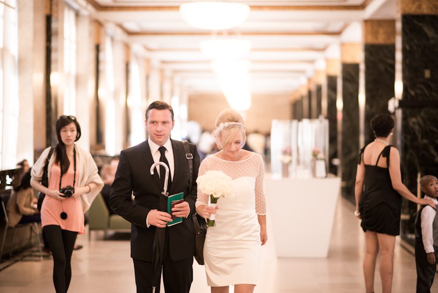 Bride and groom walk along the main hall before their New York City Hall wedding. Captured by northern NJ wedding photographer Ben Lau.