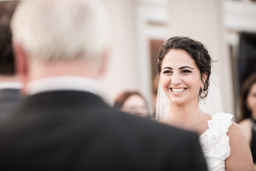 Bride Negar laughs during her outdoor wedding ceremony at the Liberty House in Jersey City, NJ. Captured by northern NJ wedding photographer Ben Lau.