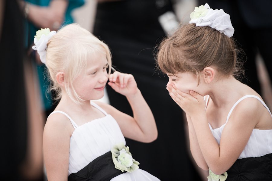Flower girls laugh during an outdoor wedding ceremony at the Liberty House in Jersey City, NJ. Captured by northern NJ wedding photographer Ben Lau.