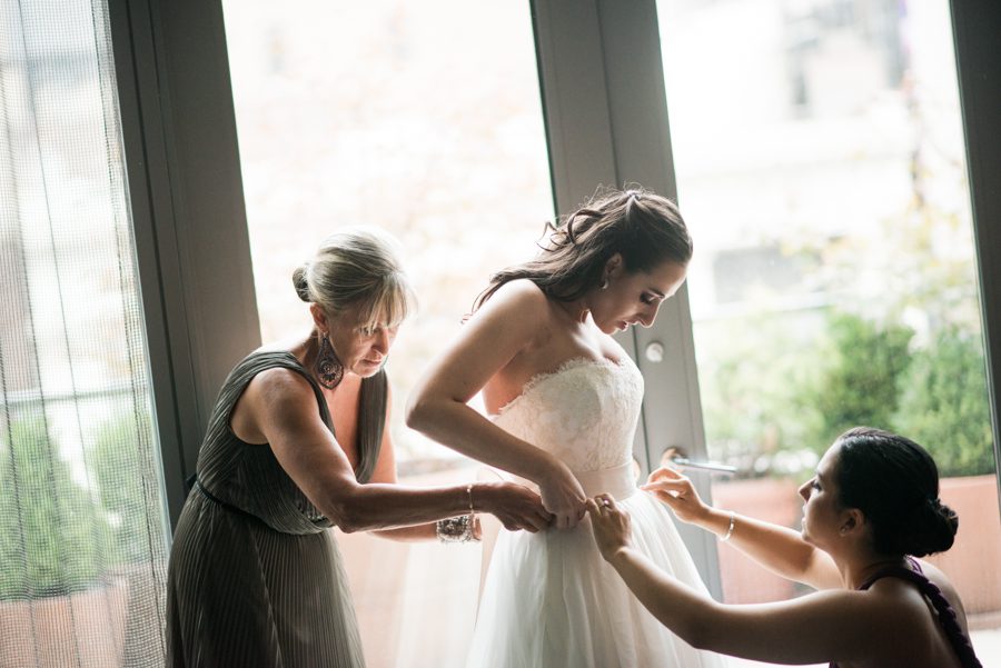 Bride puts on her dress on the morning of her wedding at the Eventi Hotel in New York City. Captured by NYC wedding photographer Ben Lau.