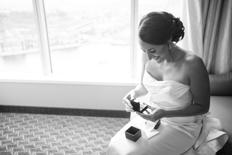 Bride opens her gift on the morning of her wedding at the Baltimore Museum of Industry in Baltimore, MD. Captured by northern NJ wedding photographer Ben Lau.