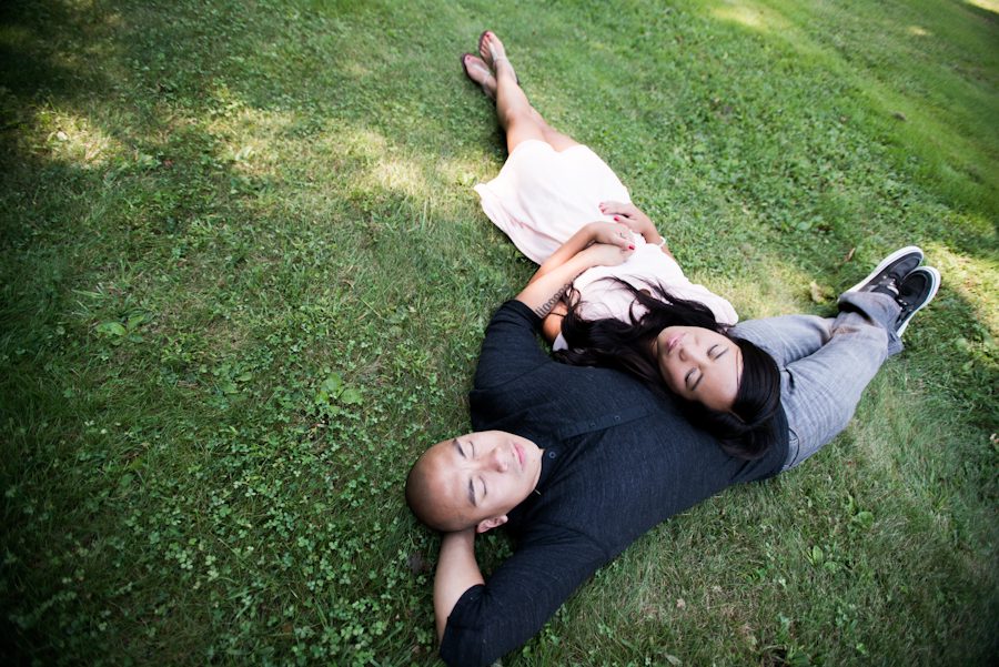 A couple lay on the grass together at the Nassau County Museum of Art during an engagement session with Ben Lau Photography.