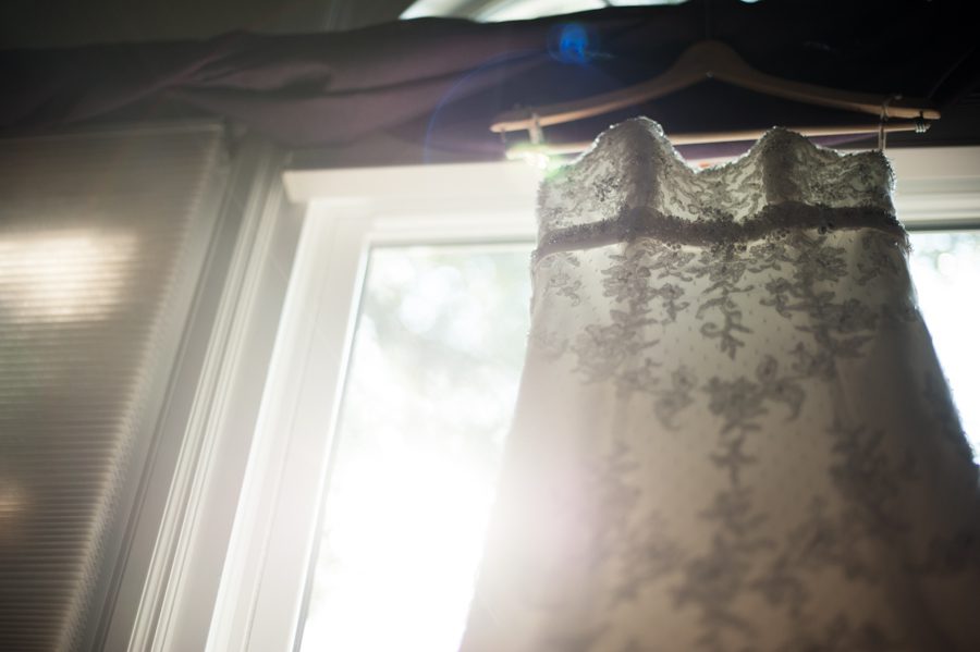 Wedding dress hangs on a window at the Neshanic Valley Golf Course in Neshanic Station, NJ. Captured by northern NJ wedding photographer Ben Lau.