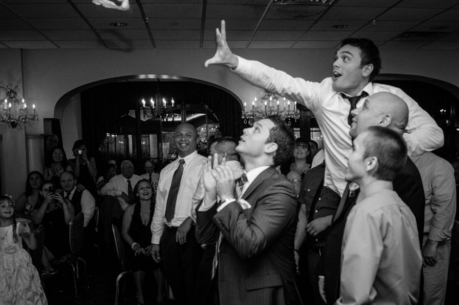 Guest attempts to catch bride's garter during their wedding reception at Perona Farms in Andover, NJ. Captured by northern NJ wedding photographer Ben Lau.