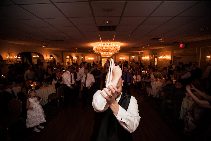 Groom about to launch garter during their wedding reception at Perona Farms in Andover, NJ. Captured by northern NJ wedding photographer Ben Lau.