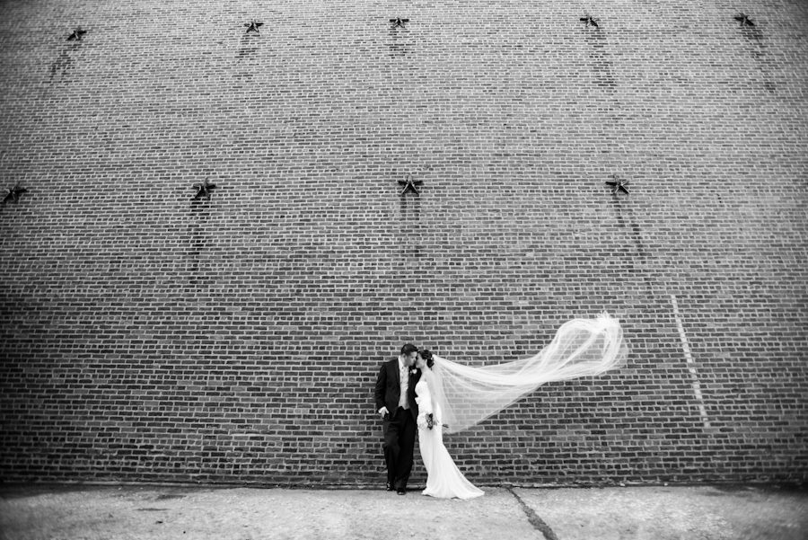 Bride and groom pose along a wall in Red Hook, Brooklyn during their bridal portraits by Ben Lau Photography.