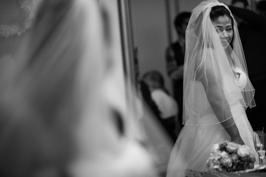 Bride looks at herself before her wedding at the Crystal Plaza in Livingston, NJ. Captured by NJ wedding photographer Ben Lau.