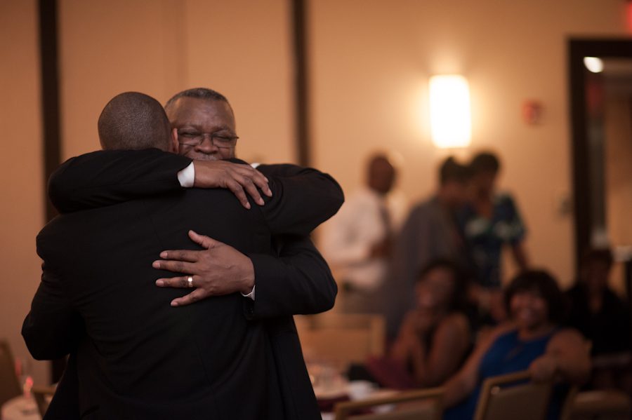 Father and son share a hug during wedding at the Marriott Crystal City in Arlington, VA. Caputred by Northern Virginia wedding photographer Ben Lau.