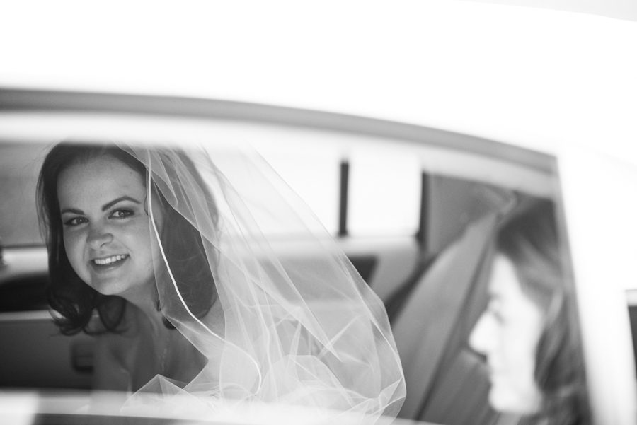 Bride's peeks out of her limo on her wedding day at Mercer Oaks in Princeton Junction, NJ. Captured by NJ wedding photographer Ben Lau.