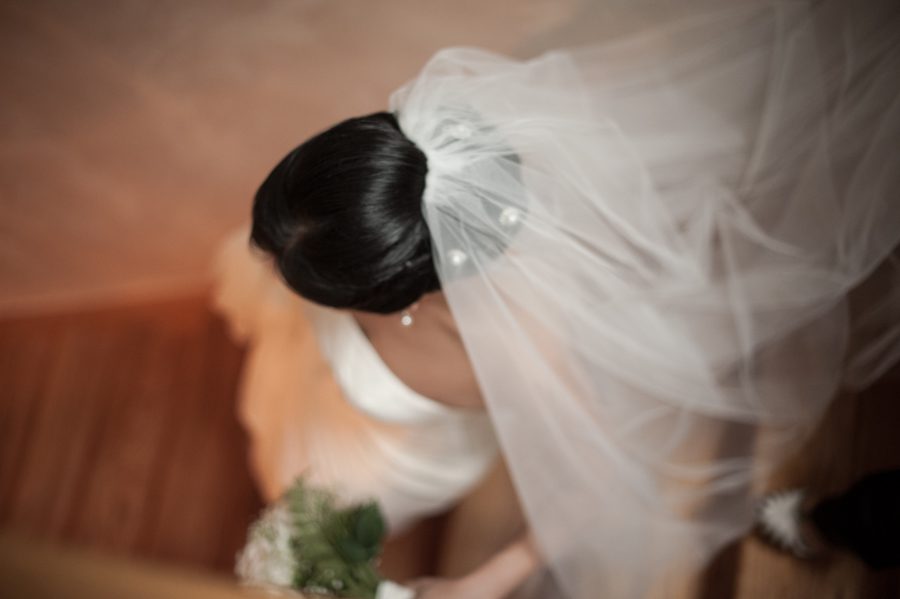 Bride descends the stairs on her wedding day in Brooklyn, NY. Captured by Ben Lau Photography.
