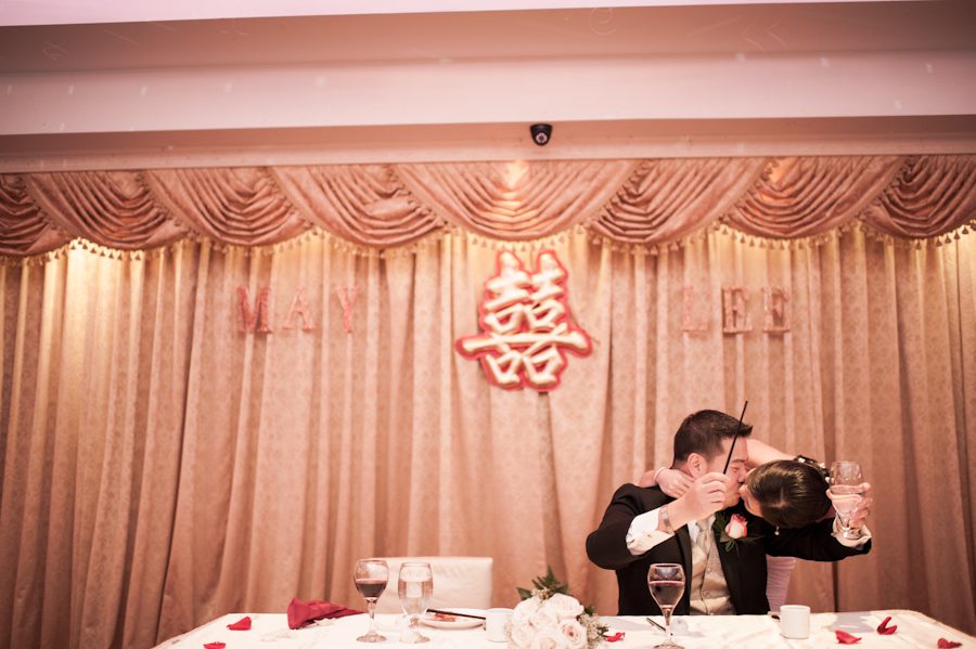 Groom taps his glass during his wedding reception at Mudan's in Flushing, NY. Captured by Ben Lau Photography.