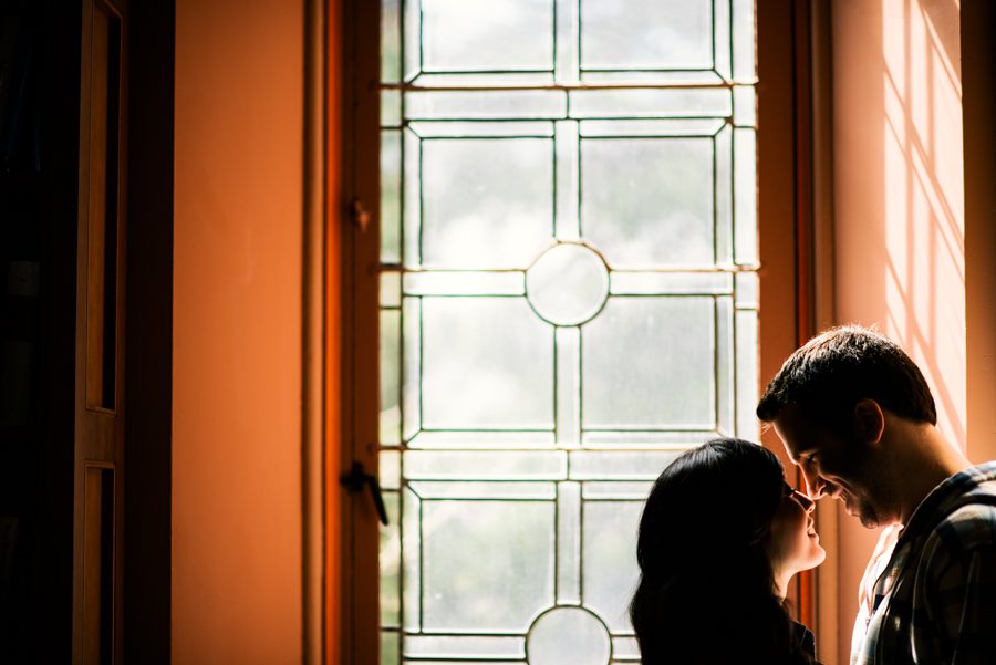 Julia and Jeff pose by a window during their engagement session at a Princeton University library.