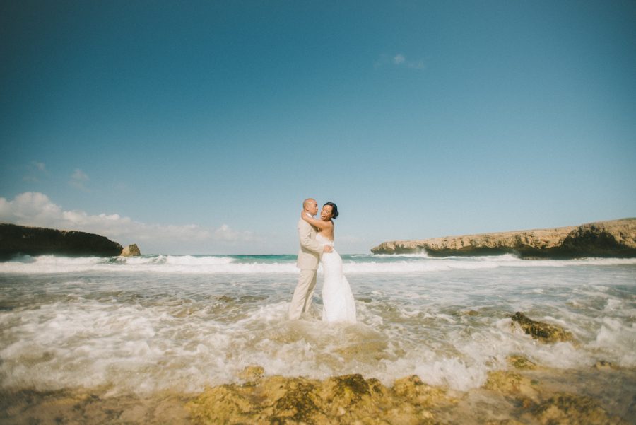 Bride and groom pose by the beach in Aruba. Captured by destination wedding photographer Ben Lau.