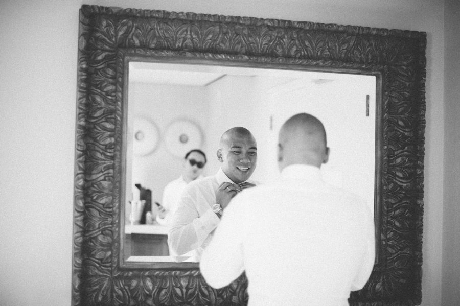 Groom adjusts his tie on the morning of his wedding at the Radisson Aruba. Captured by destination wedding photographer Ben Lau.