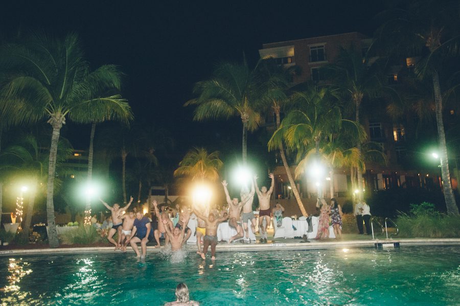 Guests jump into the pool during a Radisson Aruba wedding reception. Captured by destination wedding photographer Ben Lau.