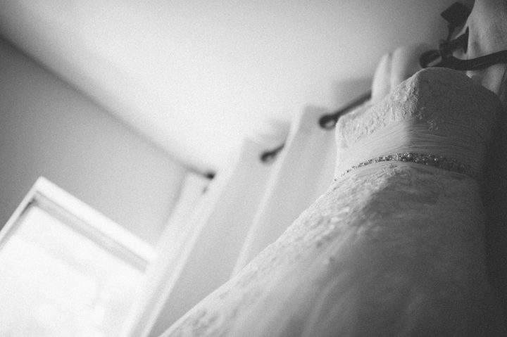 Wedding dress hangs by a window at the Liberty House in Jersey City, NJ. Captured by NYC wedding photographer Ben Lau.