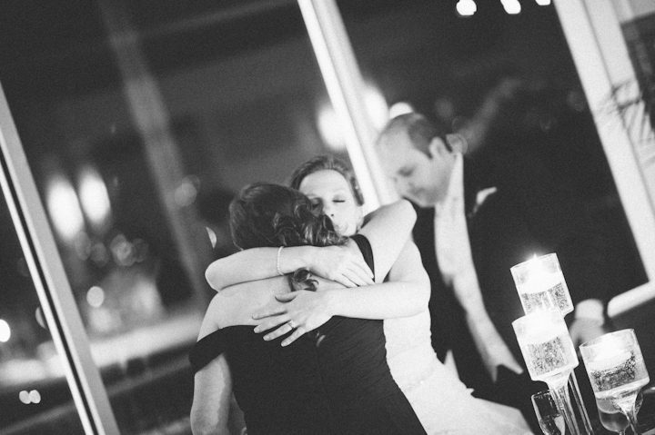 Bride hugs Matron of Honor during a wedding reception at the Liberty House in Jersey City, NJ. Captured by NYC wedding photographer Ben Lau.