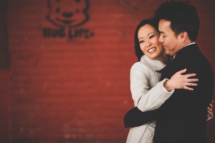 Couple poses against a wall during their engagement session in NYC. Captured by NYC wedding photographer Ben Lau.