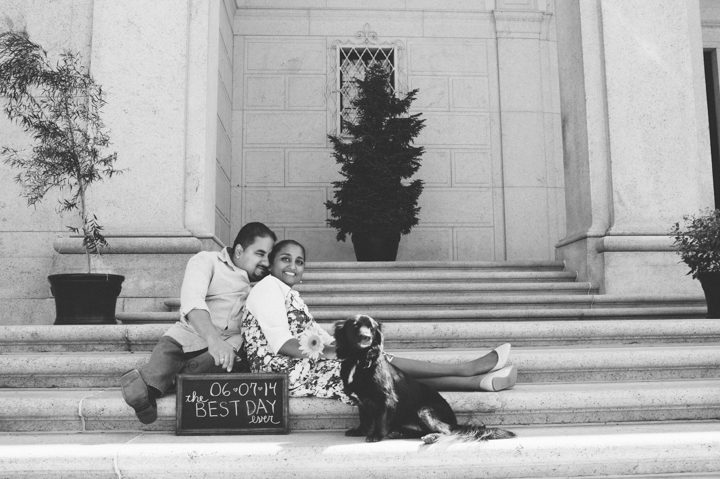 Couple sits on the steps with their save-the-date sign during their engagement session in Washington DC with Ben Lau Photography.