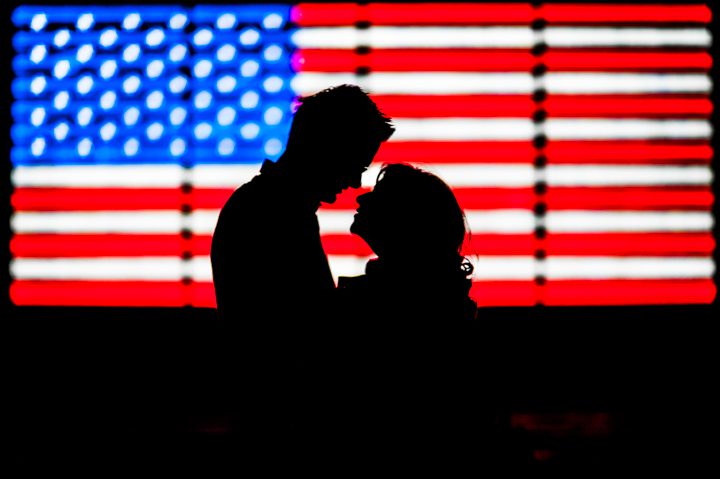 Silhouette of couple kissing in front of American Flag in Times Square during their engagement session.